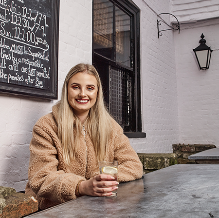 Student sitting outside a pub with a drink