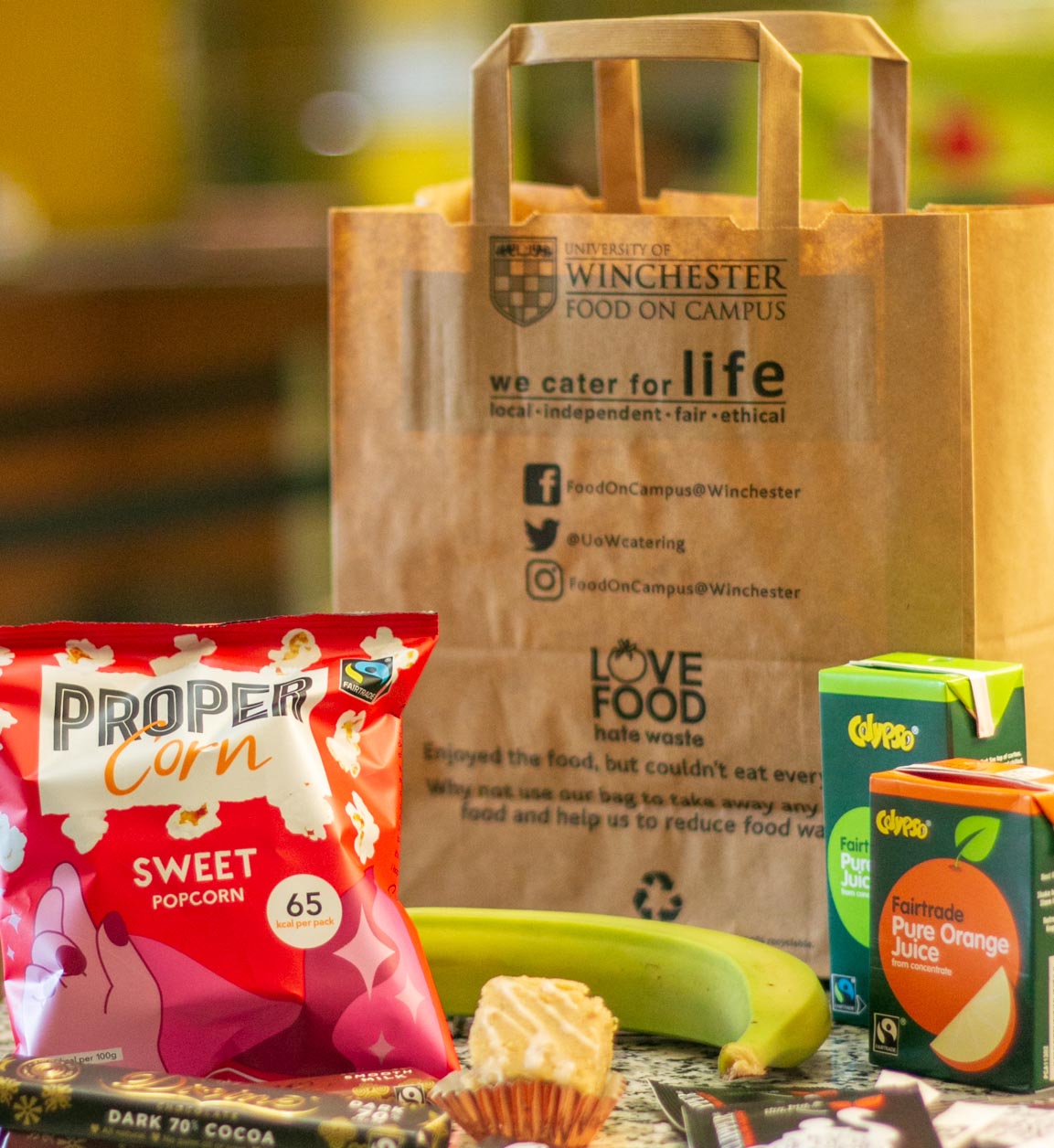 Group of fairtrade food items including a banana, bag of popcorn and drink cartons