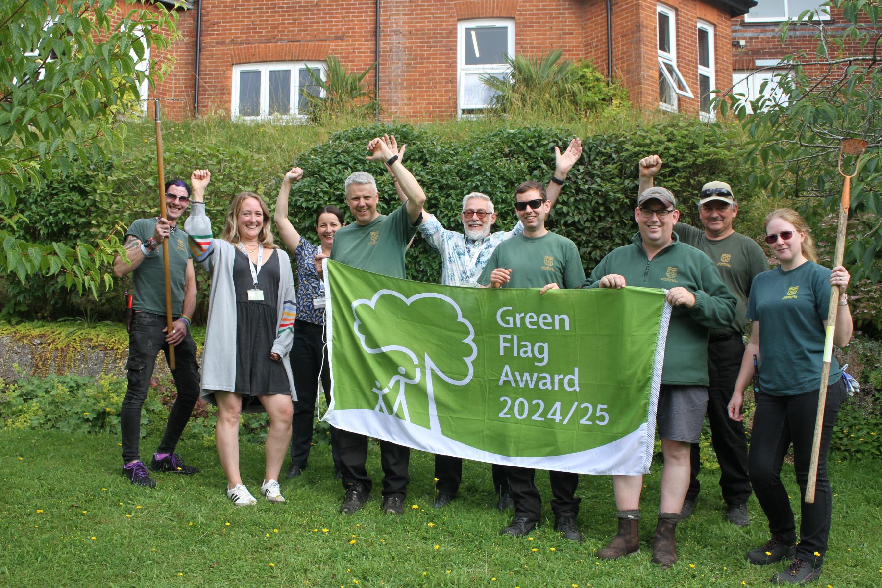 Group holding green banner emblazoned with wording Green Flag Award