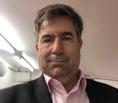 Middle aged man with dark hair in black jacket and white shirt