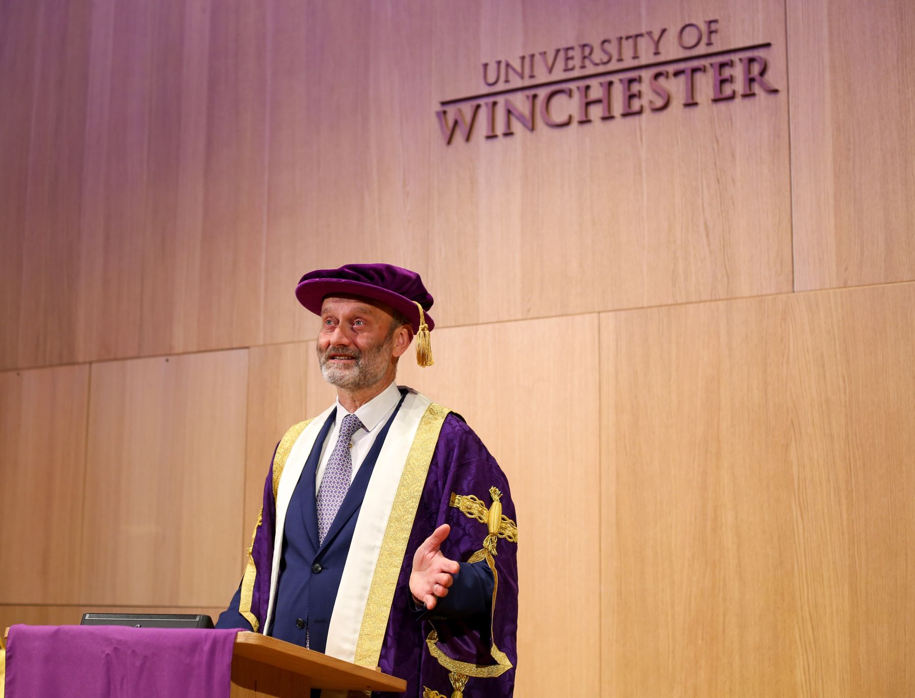 man in purple robes with University of Winchester sign in background