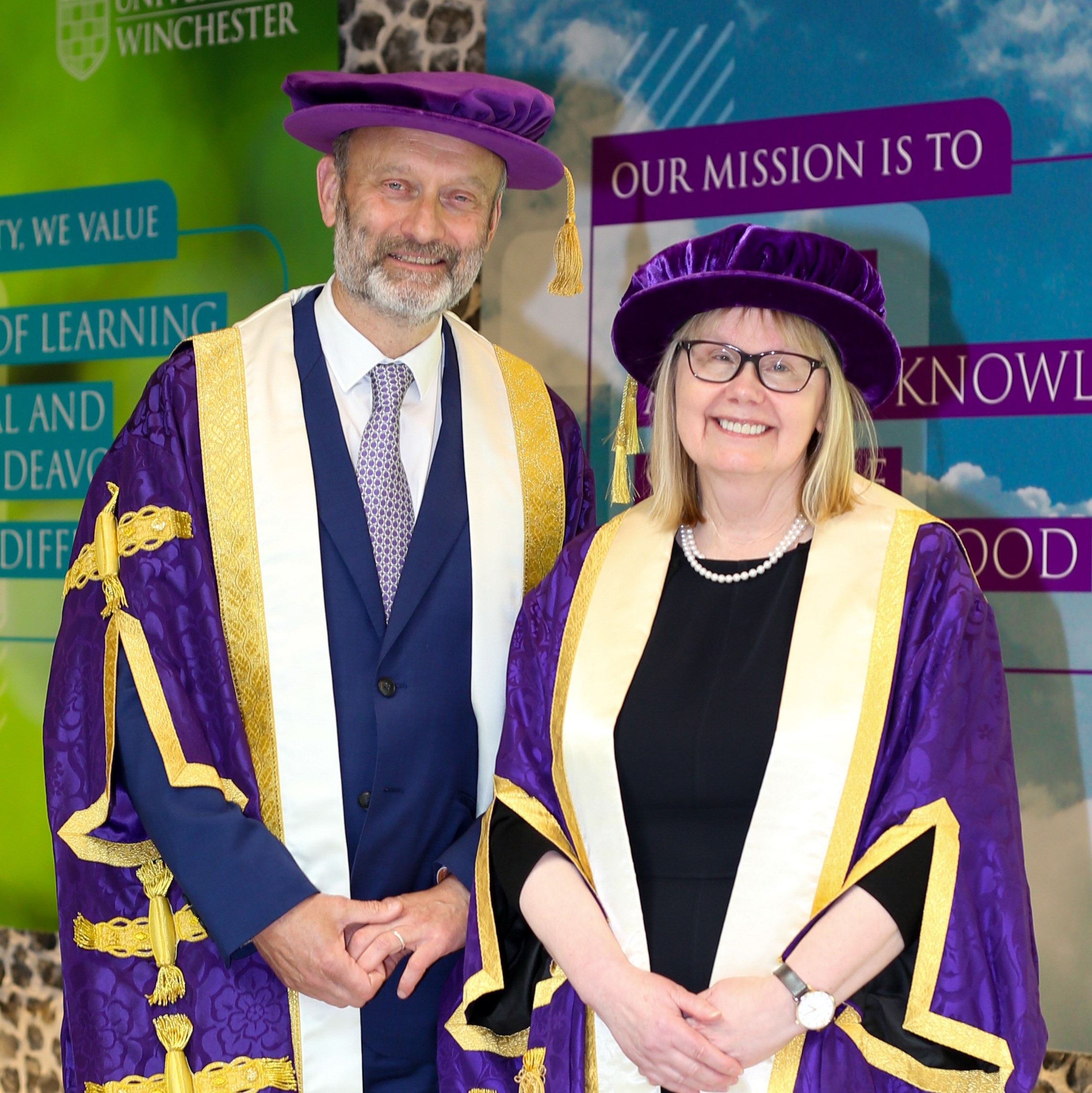 Four people in purple academic robes