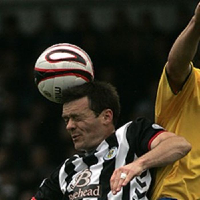 Footballer in black and white striped shirt heading ball