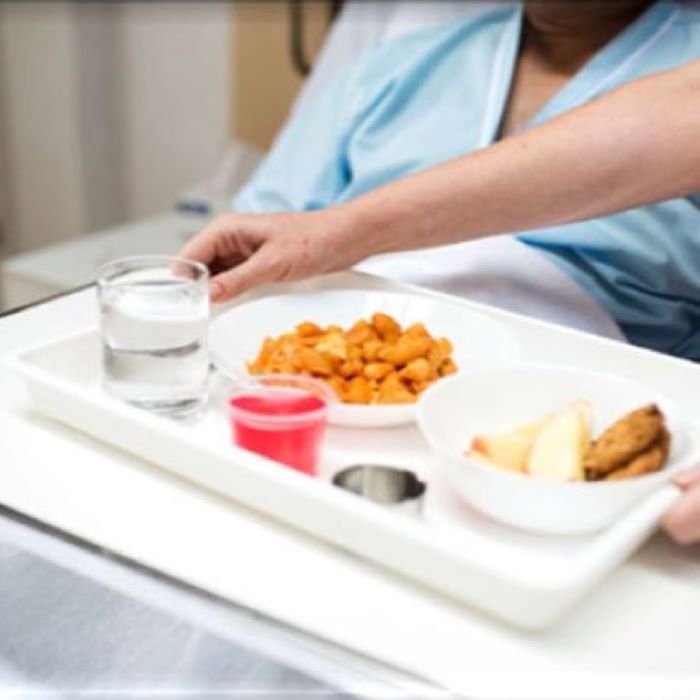 Tray of food being placed on hospital bed table