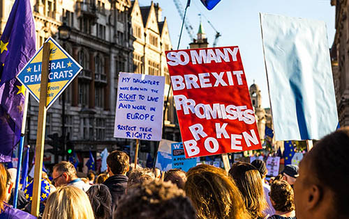 Brexit protesters marching with signs held above them reading 