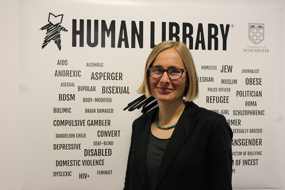 Olena Waskiewicz stands in front of Human Library banner