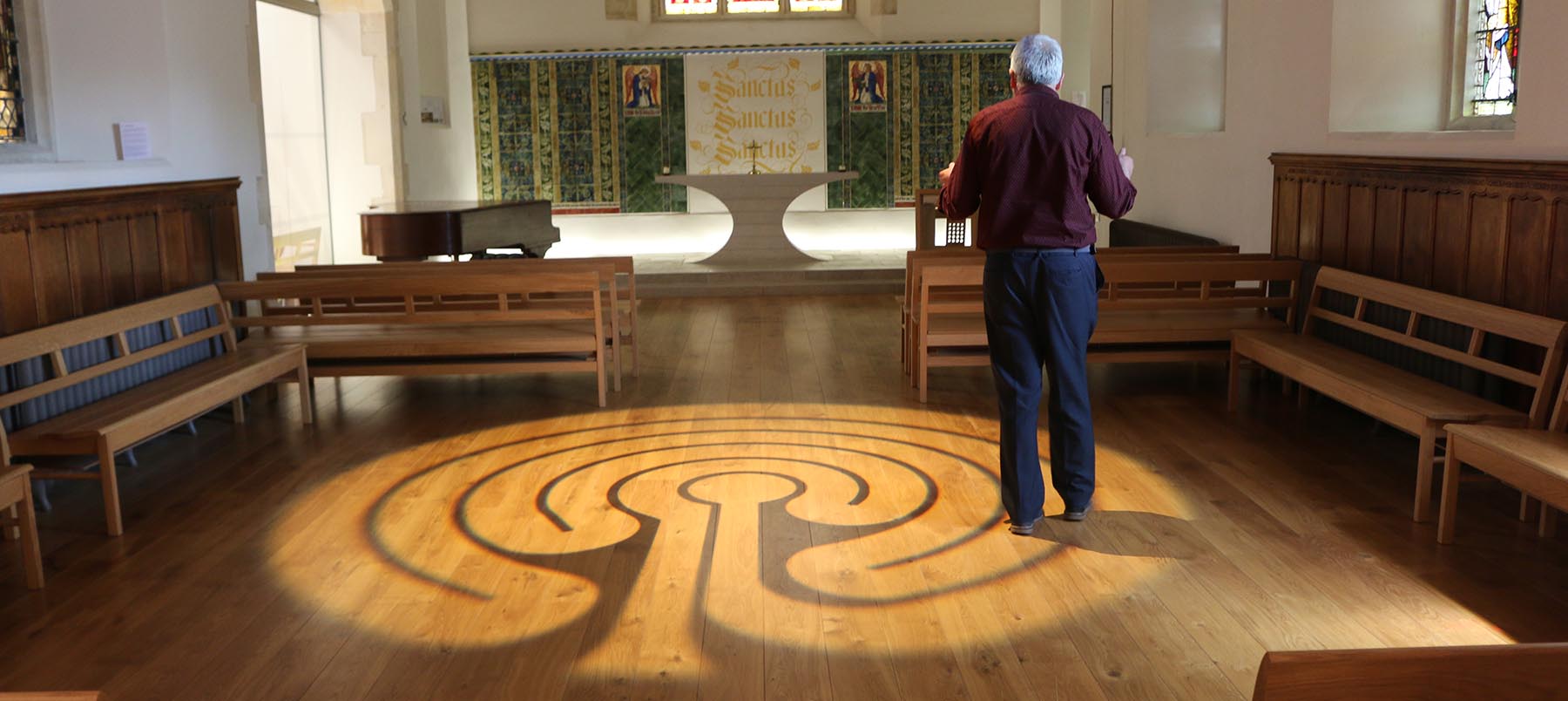 Light projection of a Labyrinth, a continuous line that weaves back on itself, on wooden floor of University of Winchester Chapel