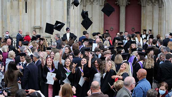 Students in graduation gowns celebrating outside Winchester Cathedral