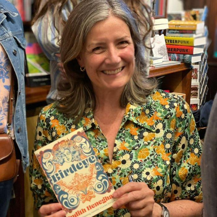 Woman in floral dress holding up book
