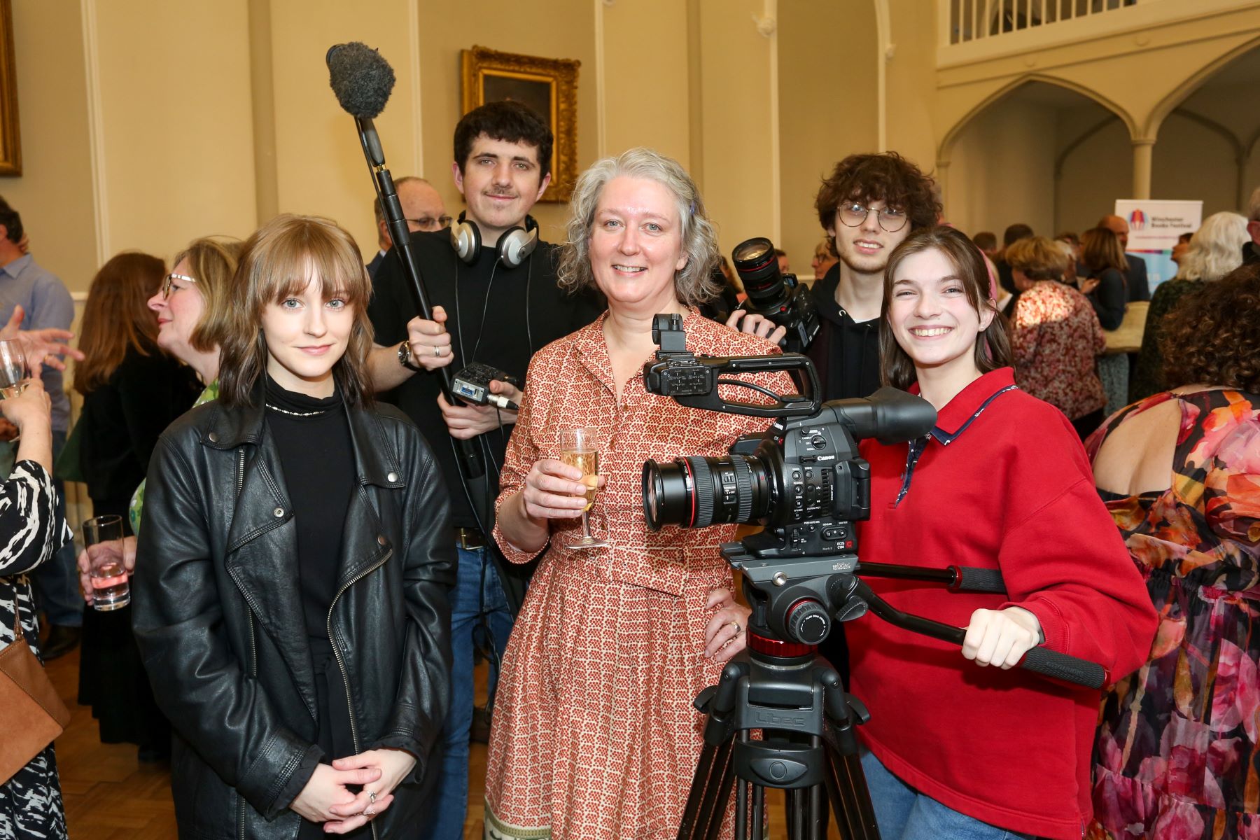 Student with camera equipment surround female author