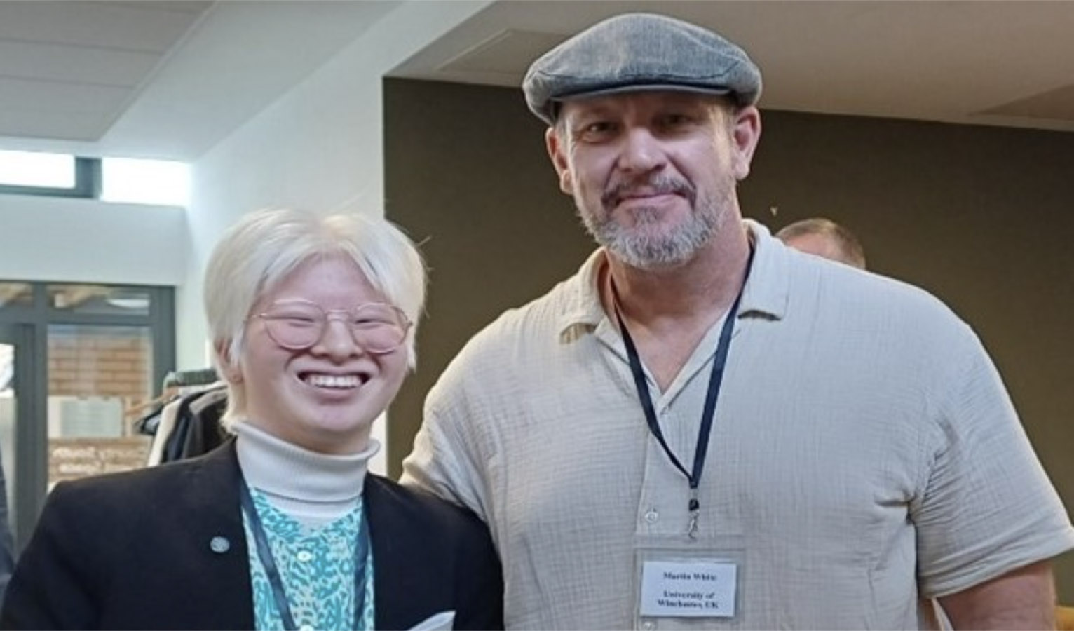 Two people smiling for the camera, one a Caucasian male, the other an Asian albino