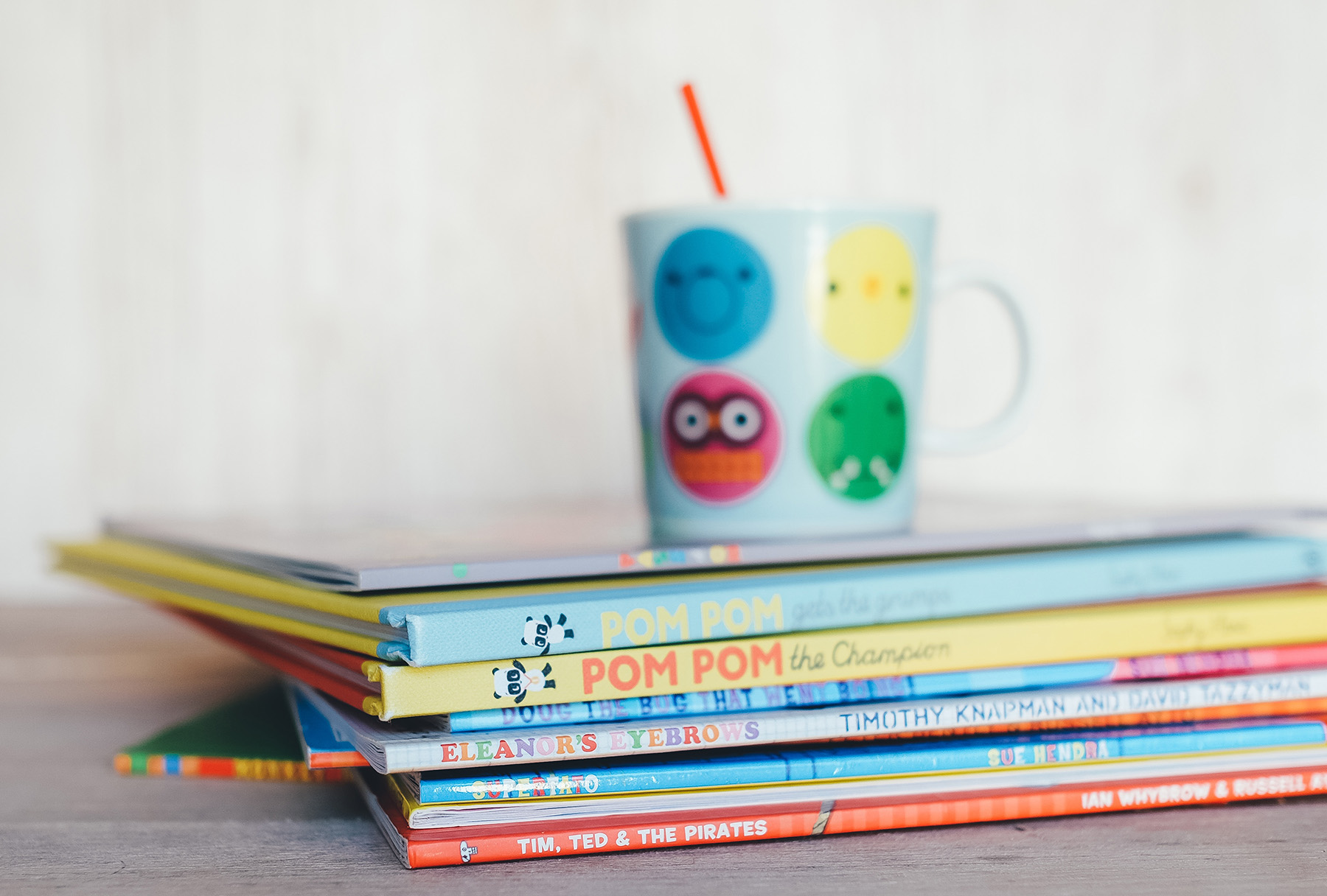 Stack of children's books with a cup on top