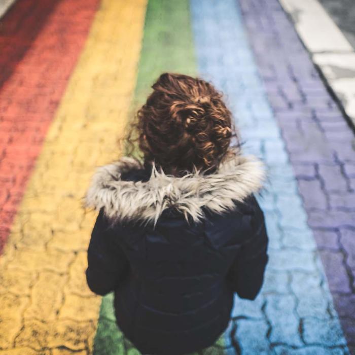 Woman looking at rainbow cobbled street