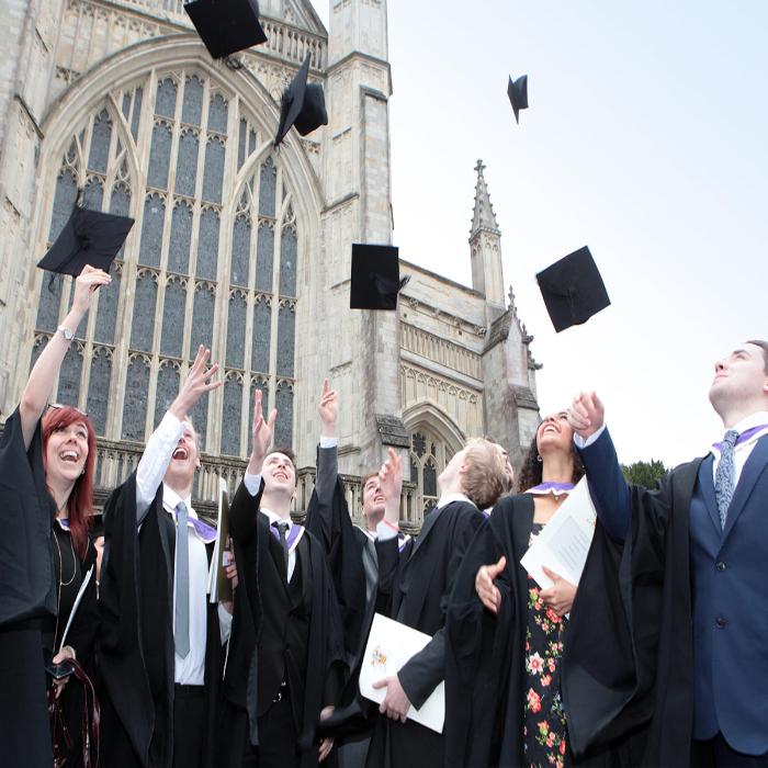 Graduates throwing caps in the air outside Winchester Cathedral