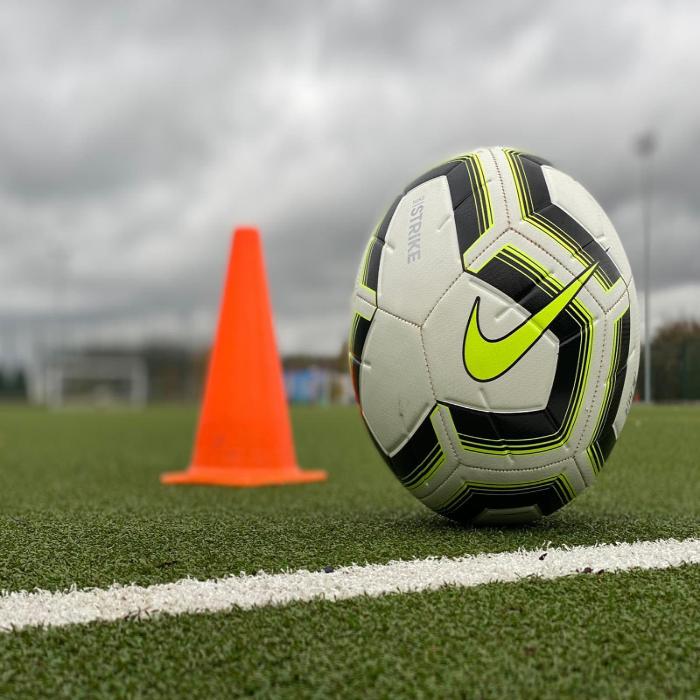 A football and cone on an all weather pitch