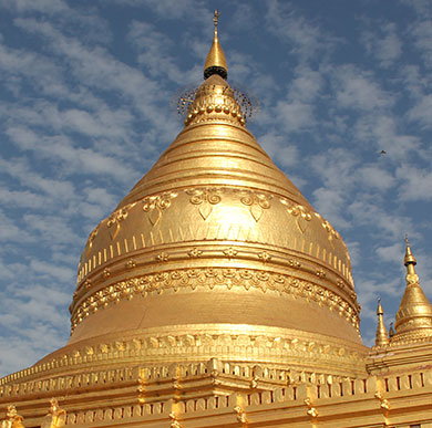 Golden dome of a Burmese temple against a blue sky