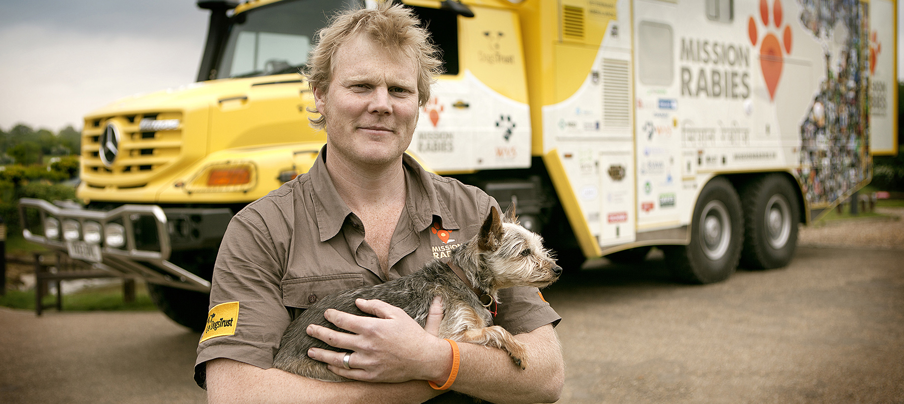 vet with dog standing in front of large lorry