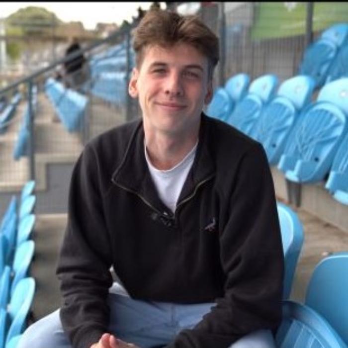A young man with dark top sitting in empty football stand