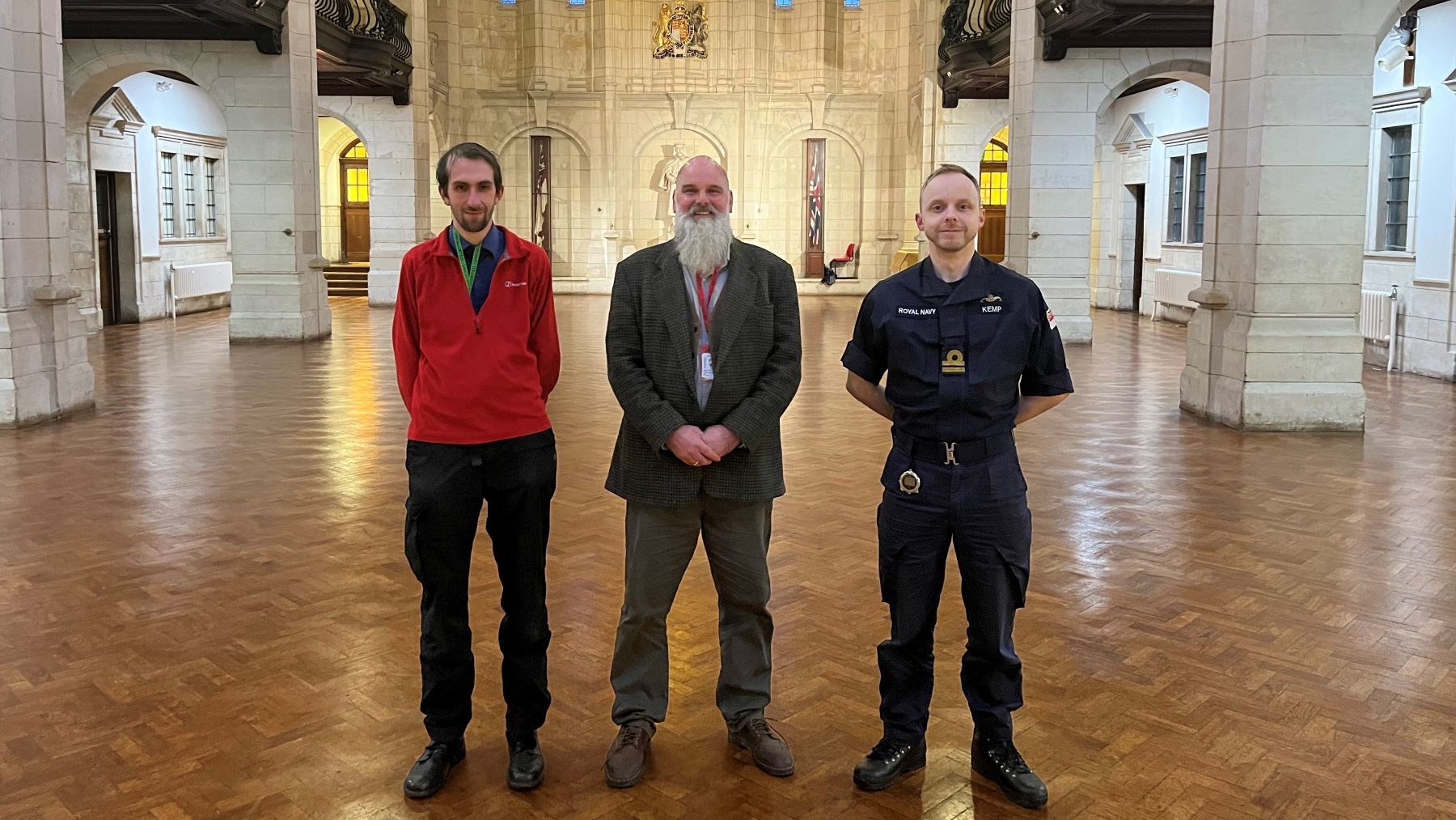 Three men standing in large impressive hall