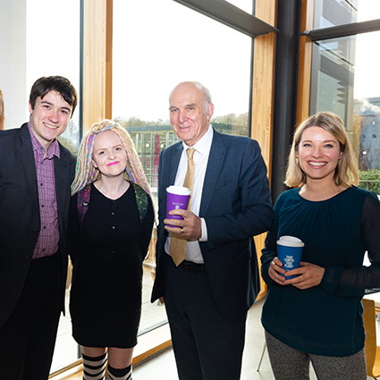 Vince Cable standing with one man and three women holding a branded reusable coffee cup