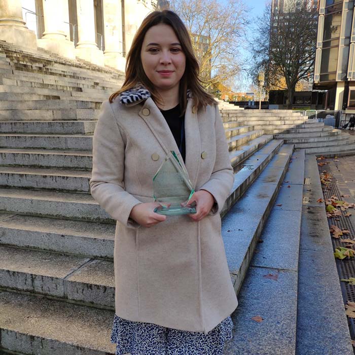 Lucy Collier standing outside on steps with her award