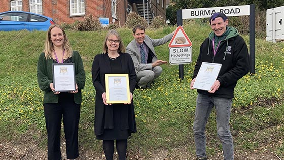 Four people outside holding hedgehog gold certificates