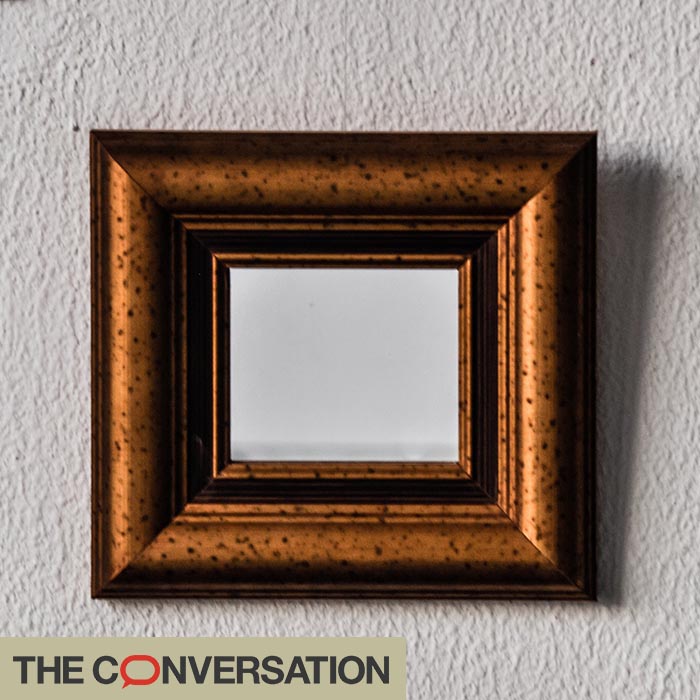 Small gold framed mirror on a white wall