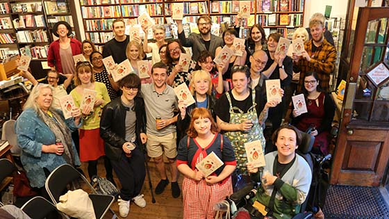 Attendees at poetry launch holding up their copies of the book