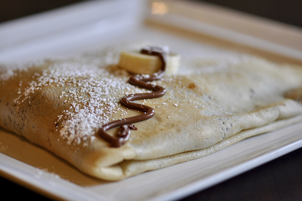 Crepe pancakes on a plate with chocolate sauce on top